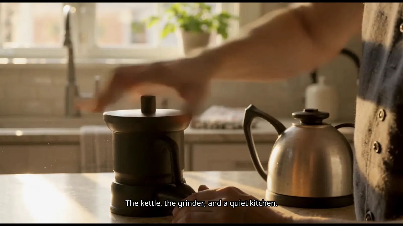 A frame from the exported video: hands reaching over a coffee grinder and a kettle on a kitchen counter, with the caption "The kettle, the grinder, and a quiet kitchen." burned in at the bottom